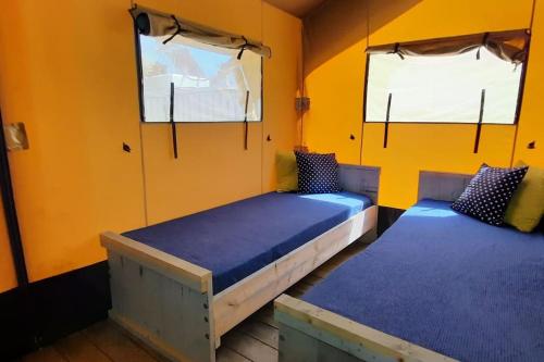 two beds in a room with yellow walls at Luxe Safari Lodge Glamping Louloudia in Pitsidia