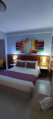 a bedroom with a large bed with paintings on the wall at Poseidonio in Piraeus