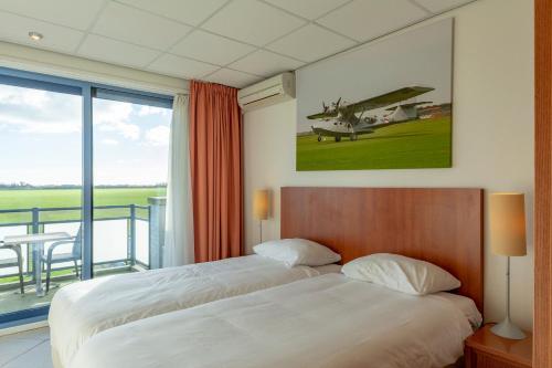 1 dormitorio con 1 cama y un avión en la pared en Studio's De Vlijt Texel, en De Cocksdorp