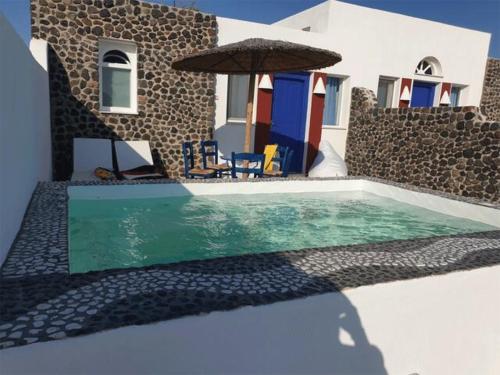 a swimming pool with an umbrella next to a house at Caldera View Resort - Adults Only in Akrotiri