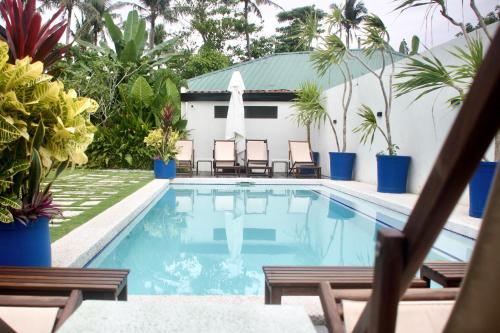 a swimming pool with chairs and plants in front of a building at Private Residences Siargao in General Luna