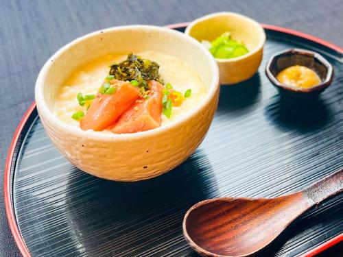 a bowl of soup on a plate with a spoon at APA Hotel Higashi Shinjuku Kabukicho Higashi in Tokyo