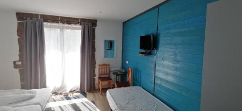 a bedroom with a blue wall with a bed and a window at Pensiunea ANA Vistisoara in Vistisoara