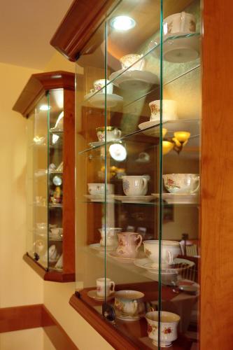 a glass cabinet with cups and dishes in it at Szerencsemák Panzió in Kehidakustány