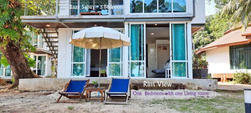 zwei Stühle und ein Tisch mit einem Regenschirm vor einem Haus in der Unterkunft Koh Mak Cococape Resort in Ko Mak
