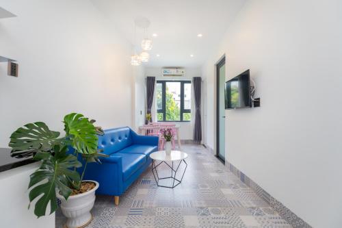a living room with a blue couch and a plant at Sea House Hotels and Apartments in Vung Tau