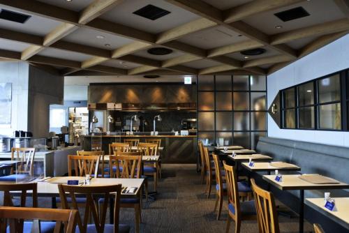 a restaurant with tables and chairs and a kitchen at Kawasaki King Skyfront Tokyu REI Hotel in Kawasaki