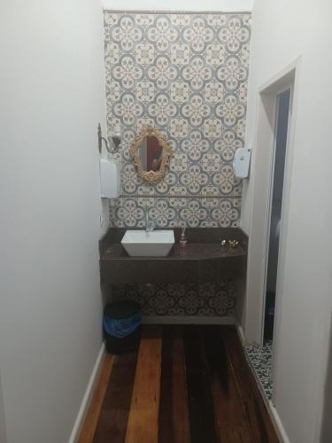 uma casa de banho com um lavatório e um espelho na parede em Casarão Hostel & Quartos Privados em Florianópolis