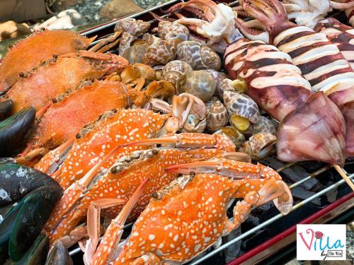 a bunch of lobster and other seafood on a grill at Villa by the Win Pattaya in Jomtien Beach