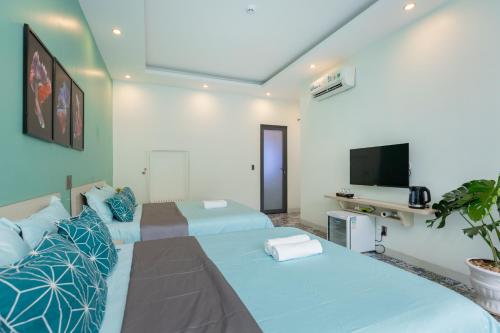two beds in a room with a tv and a room at Sea House Hotels and Apartments in Vung Tau