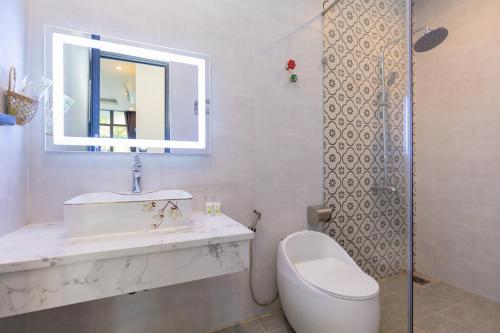 a bathroom with a sink and a toilet and a mirror at Sea House Hotels and Apartments in Vung Tau