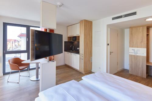 a bedroom with a bed with a television and a chair at VR-Serviced Apartments Gerstungen in Gerstungen