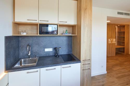a kitchen with white cabinets and a sink and a microwave at VR-Serviced Apartments Gerstungen in Gerstungen