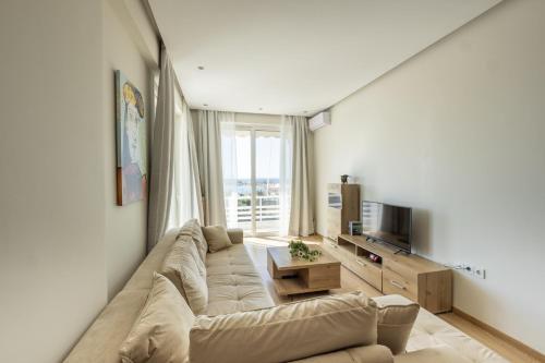 sala de estar con sofá grande y TV en Modern apt in Glyfada a Breath Away from the Sea - The View en Atenas