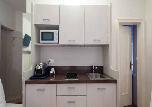 a kitchen with white cabinets and a sink and a microwave at Acquarello Swiss Quality Hotel in Lugano