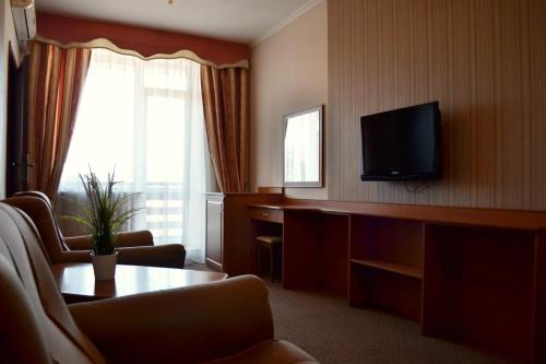 ストルィーにあるHotel Perlyna ARSのテレビ、テーブル、椅子が備わるホテルルームです。