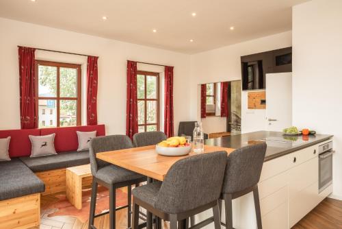 a kitchen and living room with a wooden table and chairs at Hotel ChiemseePanorama in Gstadt am Chiemsee