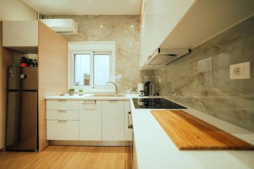 uma cozinha com armários brancos e um frigorífico preto em The Sandbox em Atenas