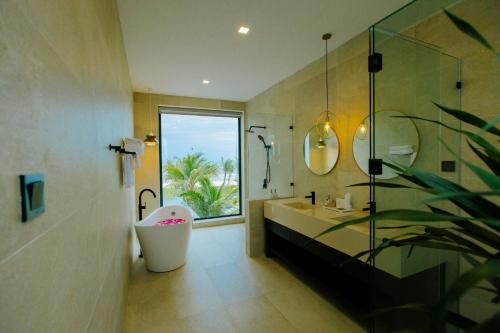 baño con bañera, lavabo y ventana en Perolas Villas Resort Powered by ASTON, en Phan Thiet