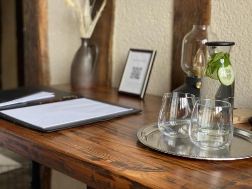 una mesa de madera con dos vasos y un ordenador portátil. en La Tour aux Grains chambres autonomes en Romorantin