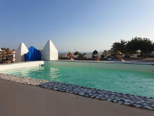 a swimming pool with turquoise water and white structures at Caldera View Resort - Adults Only in Akrotiri