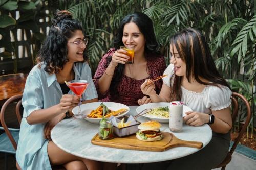 three women sitting at a table with food and drinks at Grand Mercure Bangalore - An Accor Brand in Bengaluru