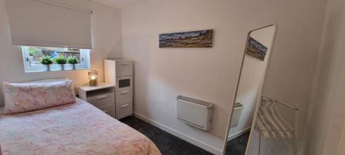 une petite chambre avec un lit et un miroir dans l'établissement Merchantcityflat, à Glasgow