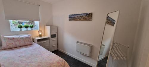 a small bedroom with a bed and a mirror at Merchantcityflat in Glasgow