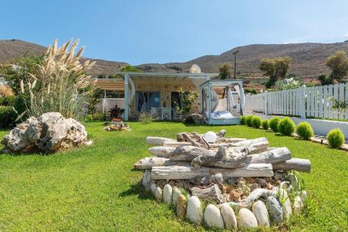 a yard with a pile of logs in the grass at Artemis Seafront Stone Studio in Petres