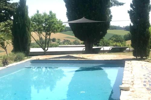 una piscina azul con sombrilla y árboles en Stunning 21-Bed Cottage in La Sauvetat 2 houses, en La Sauvetat