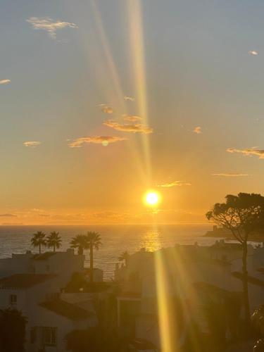 a sun setting over the ocean with a city at Miraflores Beachfront Penthouse in Mijas Costa