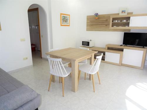 a kitchen with a wooden table and two white chairs at AL101 apartamento, céntrico y piscina in Alcossebre