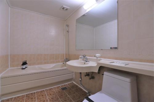 ein Badezimmer mit einem Waschbecken, einer Badewanne und einem WC in der Unterkunft Hani Motel in Daejeon