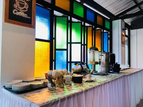 a table with plates and cups and stained glass windows at The Rubber Hotel Phuket in Thalang
