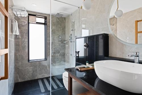 uma casa de banho com uma banheira, um lavatório e um espelho. em WelcomHeritage Ayatana, Ooty em Ooty