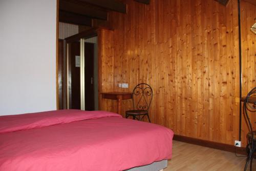 1 dormitorio con cama roja y pared de madera en maison de marie en Doussard