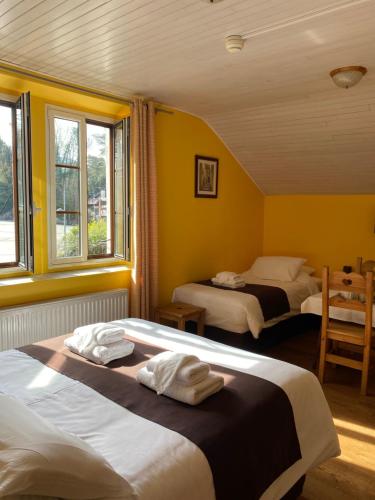 two beds in a room with yellow walls and windows at Hôtel du Château in Annecy