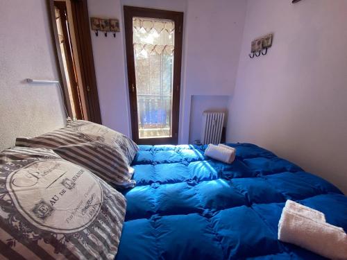 a large blue bed in a room with a window at Hostdomus - Grand Villard Suite in Sauze d'Oulx