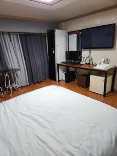 a room with a bed and a desk with a monitor at Hani Motel in Daejeon