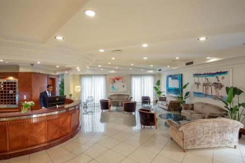 a man standing at a reception desk in a lobby at Best Western Hotel Viterbo in Viterbo