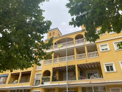 ein gelbes Gebäude mit einem Balkon und einem Uhrturm in der Unterkunft Almoradi in Almoradí
