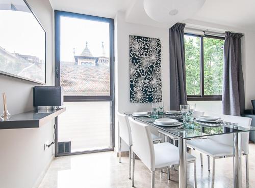a dining room with a glass table and white chairs at Picasso Suites in Barcelona