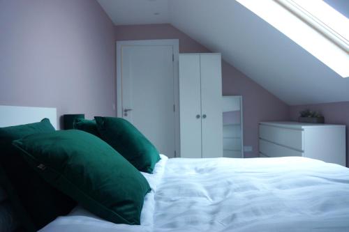 a bedroom with a bed with green pillows at Àit Sèan Òg - 2bedroom self catering apartment 