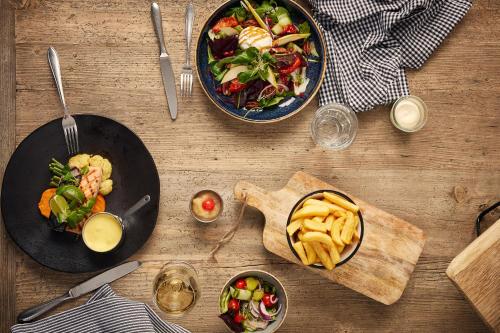 une table en bois avec deux assiettes de nourriture et de frites dans l'établissement Van der Valk Cuijk - Nijmegen, à Nimègue