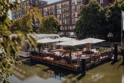 a restaurant with tables and white umbrellas on a river at Mercure Hotel Hamburg City in Hamburg