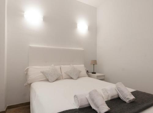 a white bedroom with a white bed with pillows at Picasso Suites in Barcelona