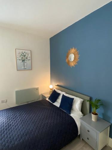a bedroom with a bed with a blue wall at London Road Flats - Free WIFI, washing machine, smart TV, easy access to A50 in Derby