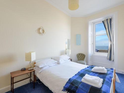 a white bedroom with a bed and a window at Driftwood in North Berwick