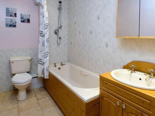 a bathroom with a toilet and a tub and a sink at Driftwood in North Berwick