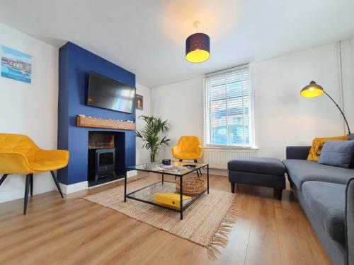 ein Wohnzimmer mit einem Sofa und einer blauen Wand in der Unterkunft Blue Horizon Holiday Cottage - 4 Minute Walk to the Beach in Weymouth